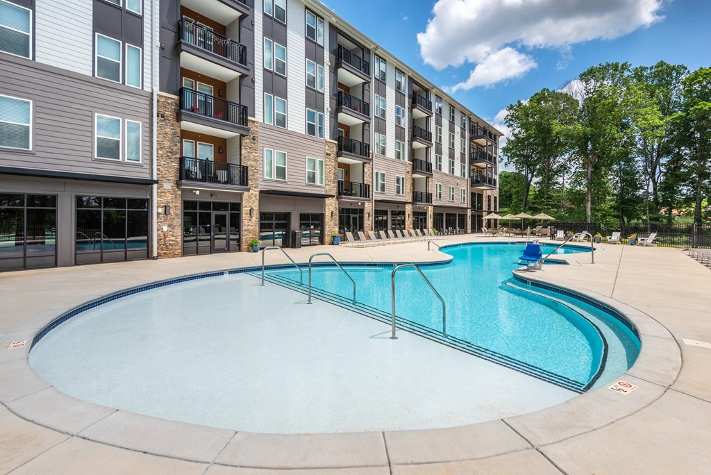 an apartment swimming pool with an apartment building in the background