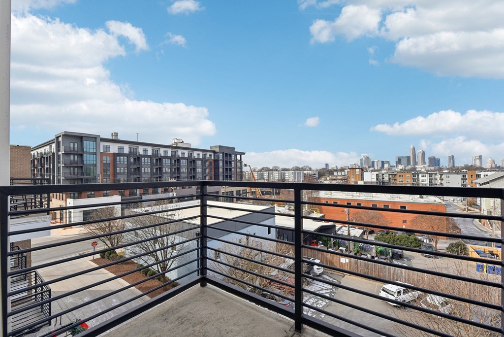 A balcony overlooks a parking lot and buildings.
