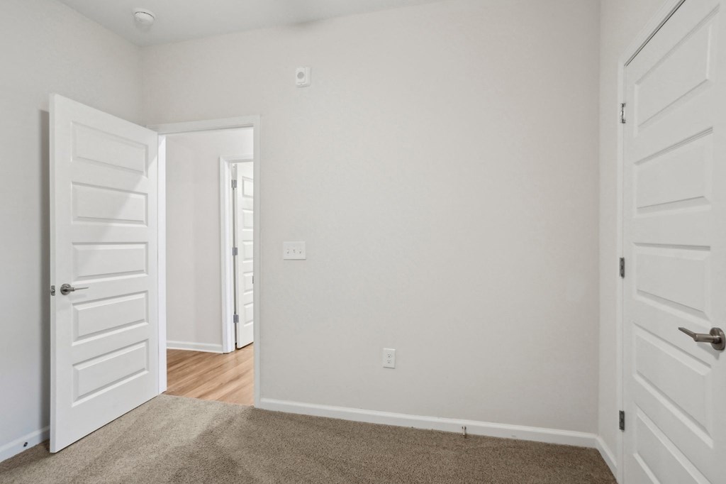 A room with a white door and a carpeted floor.