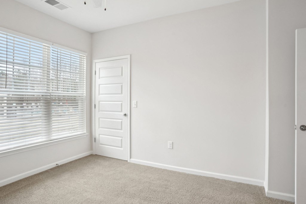 A room with a white door and carpeted floor.