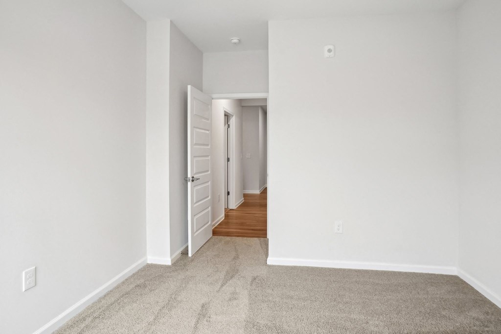 A hallway with a carpeted floor and white walls.
