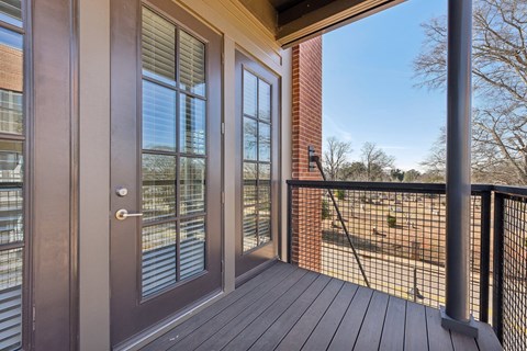 A deck with a glass door and a black railing.