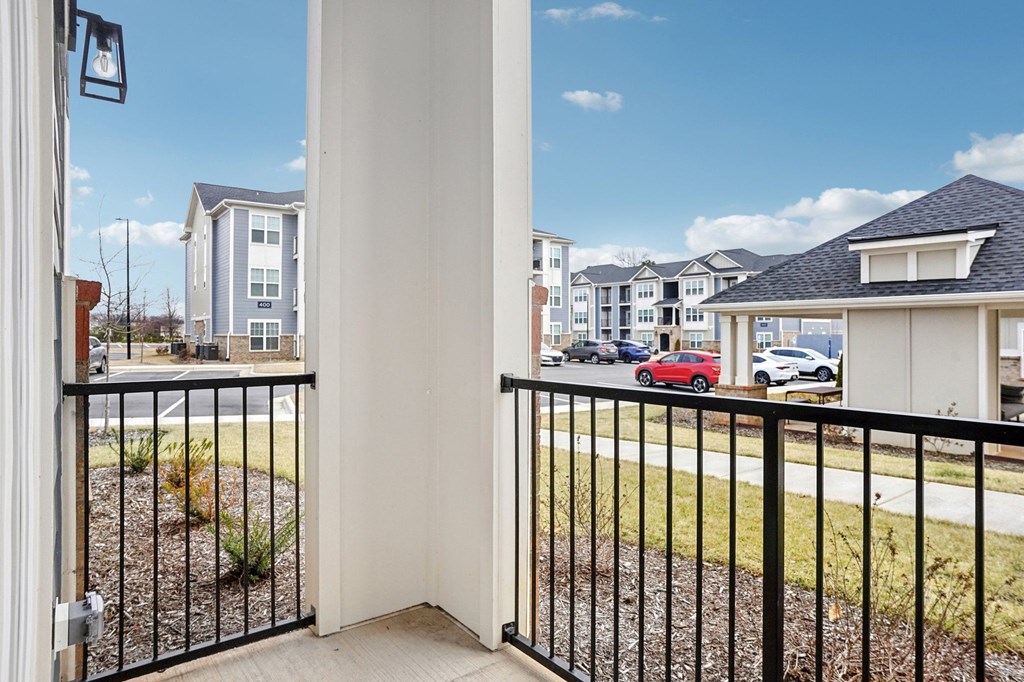 A view from a balcony looking out at a row of houses and cars.