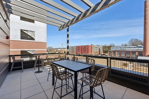 A patio with a table and chairs overlooking a train track.
