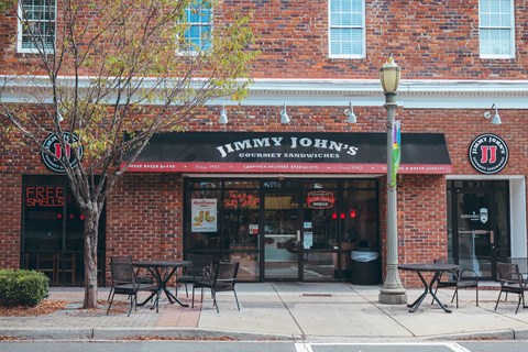 the front of a restaurant with a black awning and tables and chairs