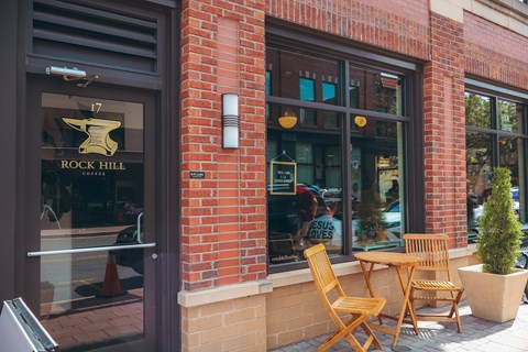 a brick building with tables and chairs outside of rock hill cafe