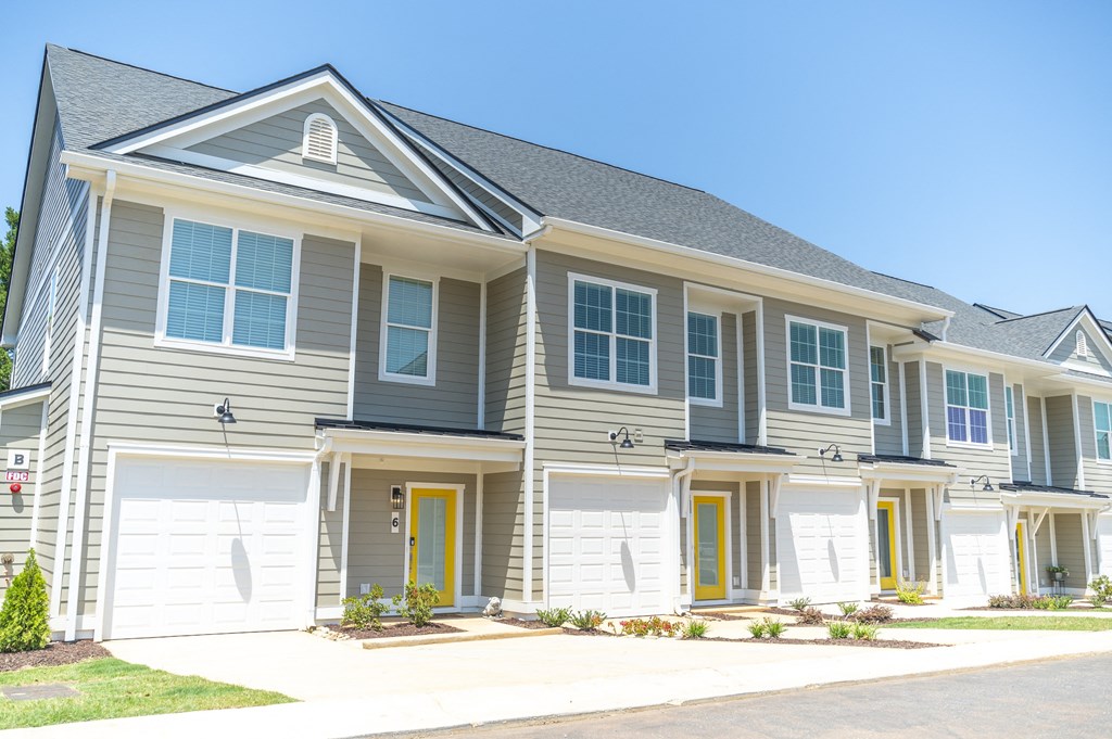 a row of houses with yellow doors and grey siding at Landon Green Artisan Cottages Apartments, North Carolina, 28601