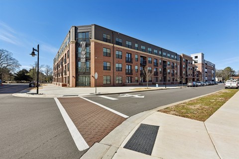 A modern building with a glass facade is situated on a street corner.