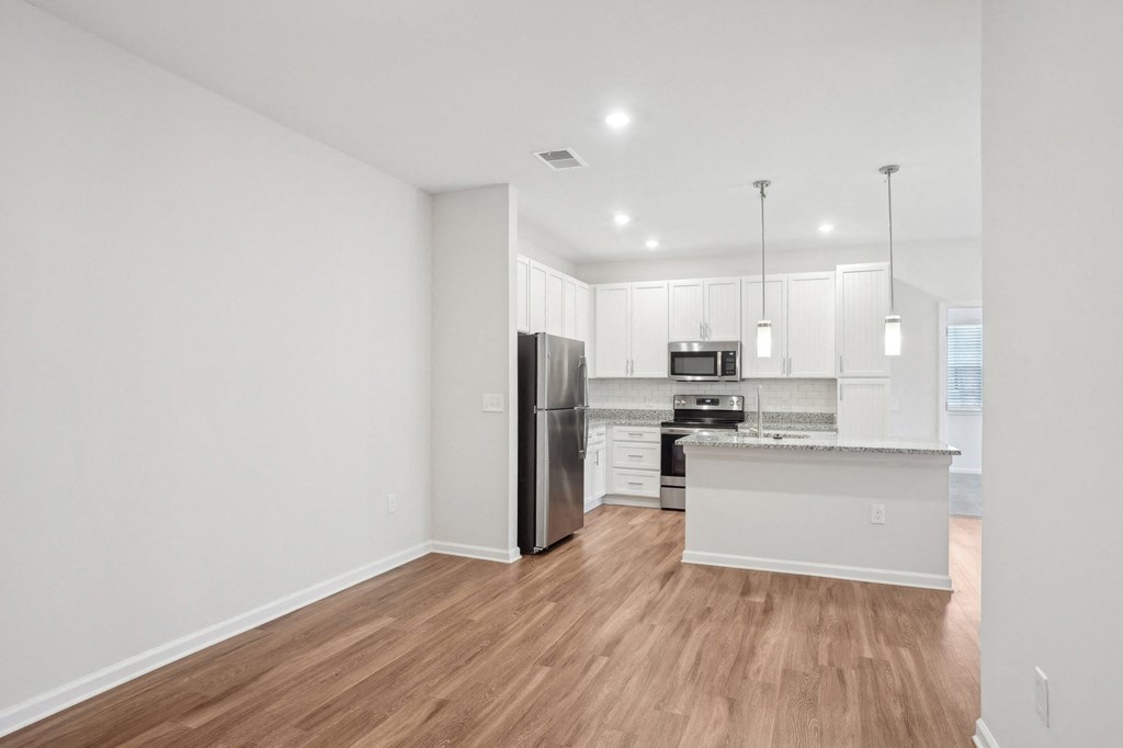A modern kitchen with wooden floors and stainless steel appliances.