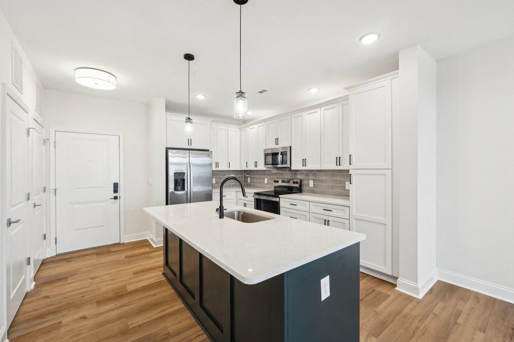 A kitchen with a white counter top and wooden floors.
