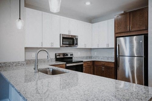 a kitchen with a marble counter top and a stainless steel refrigerator