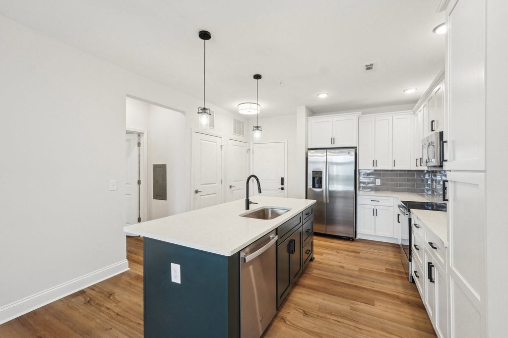 A modern kitchen with a white island and stainless steel appliances.