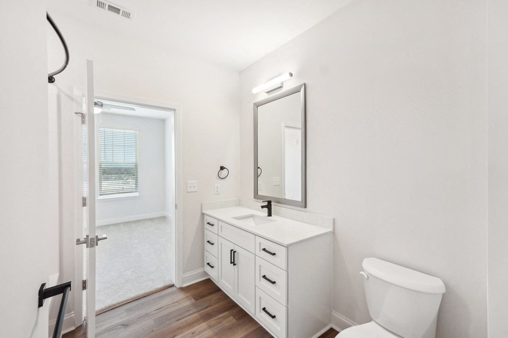 A white bathroom with a toilet, sink, and mirror.