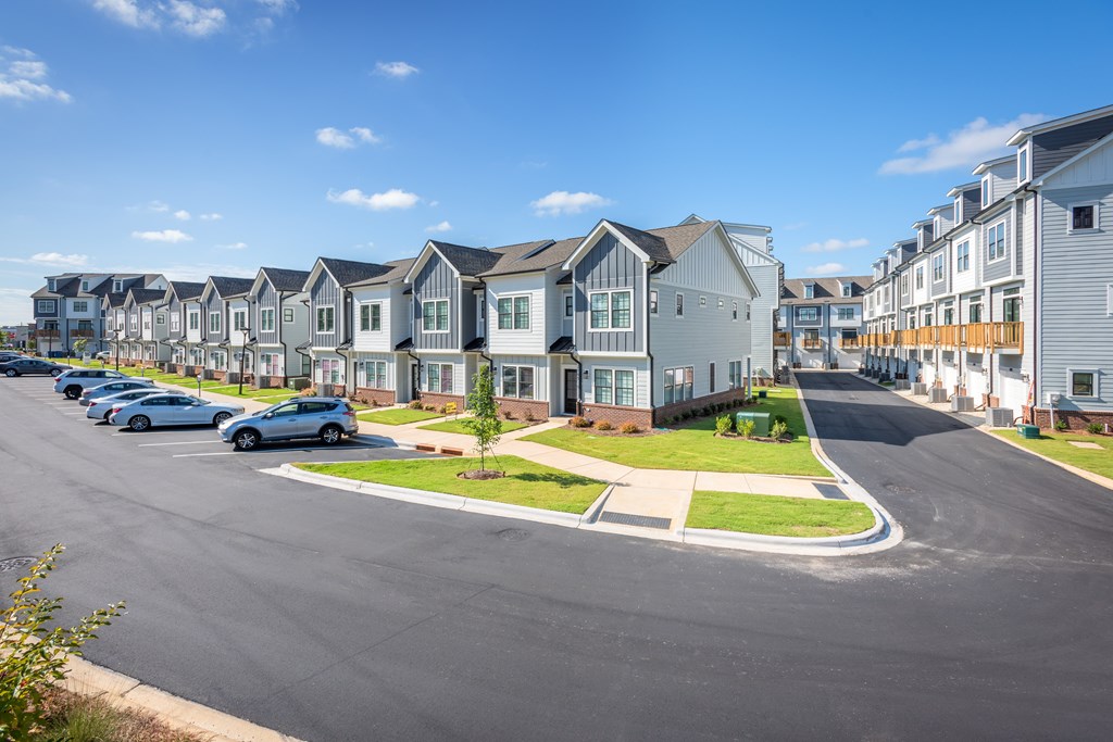 A row of houses with cars parked in front.
