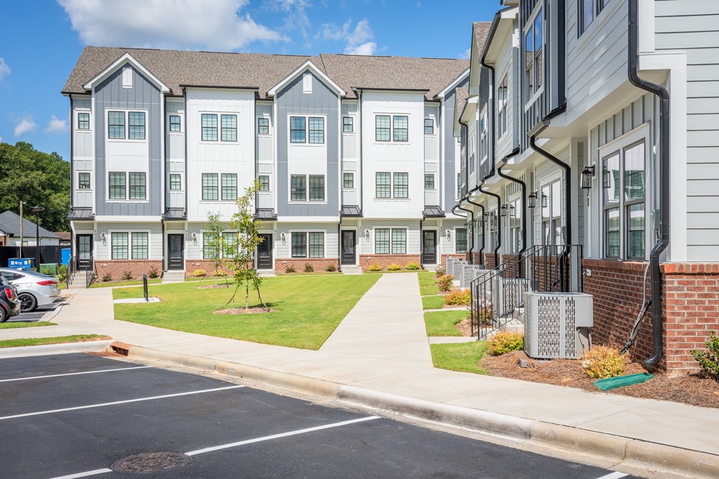 A row of townhouses with a parking lot in front.