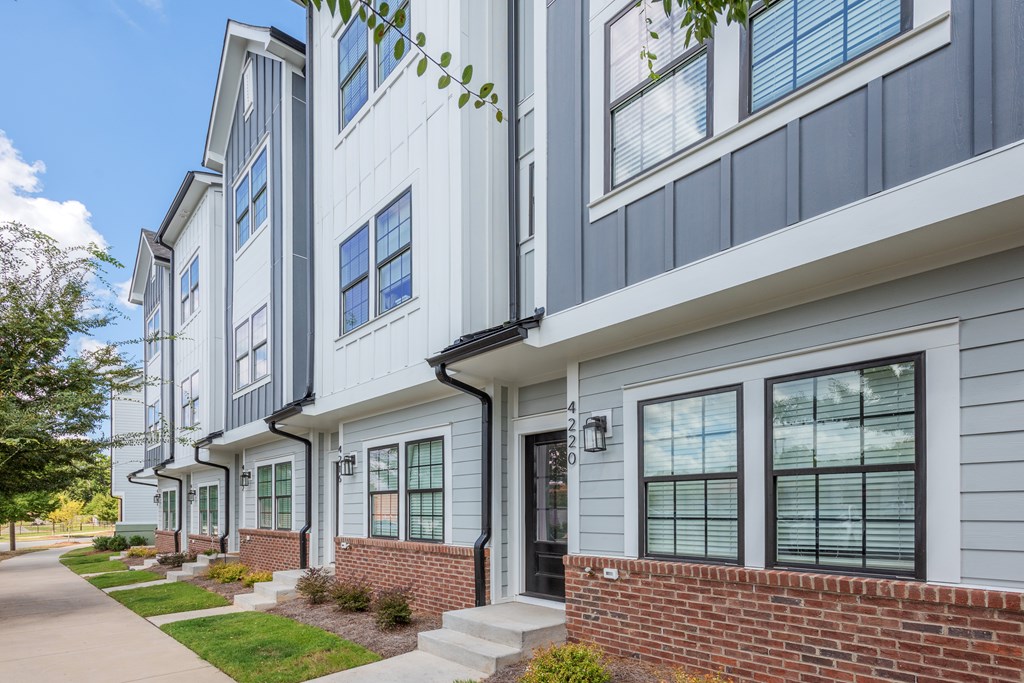 A row of townhouses with a sidewalk in front.