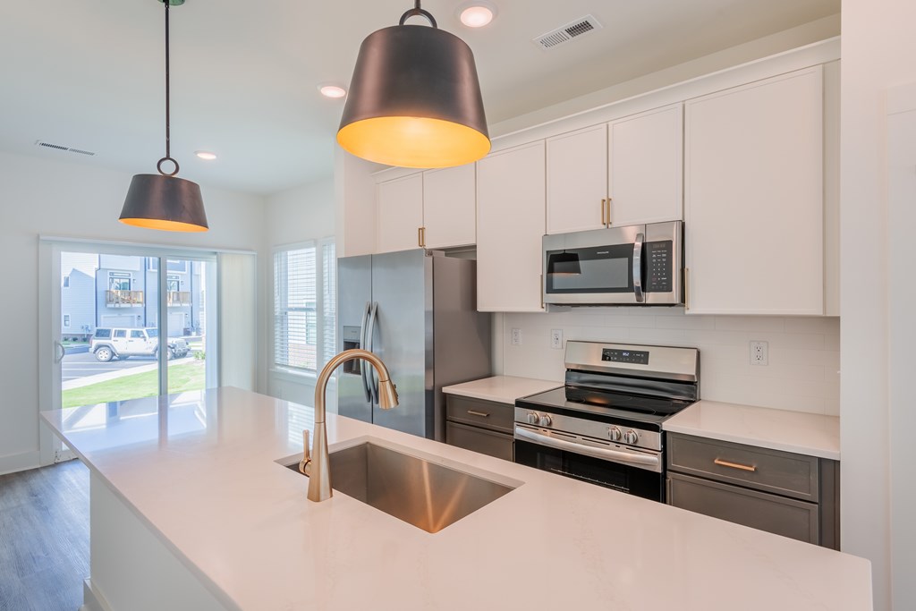 A modern kitchen with a white countertop and stainless steel appliances.
