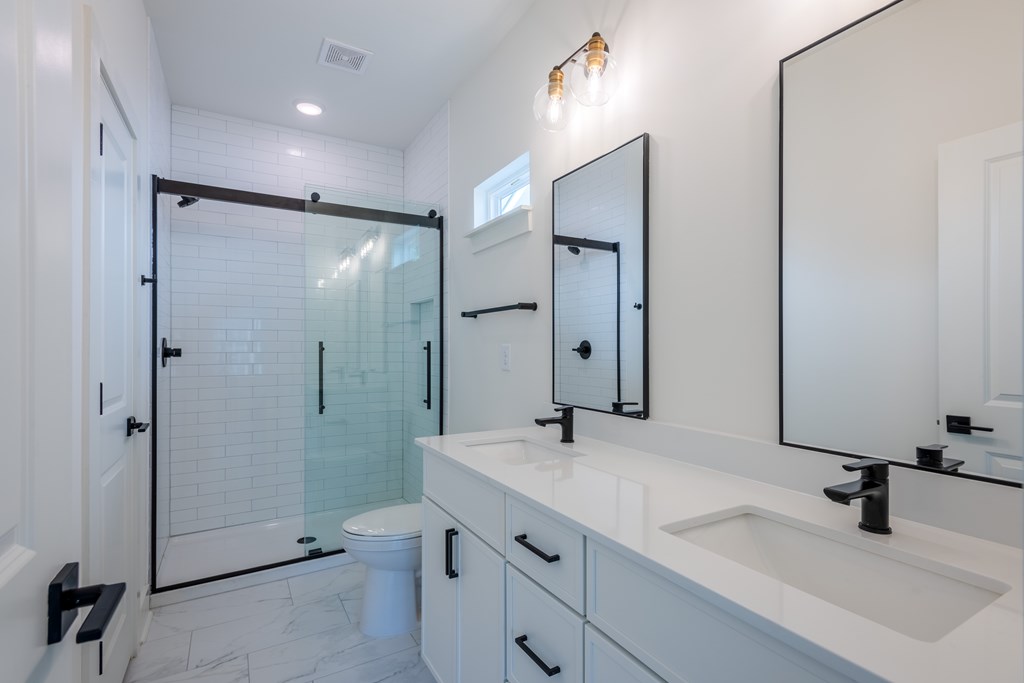 A bathroom with a white counter top and a walk in shower.