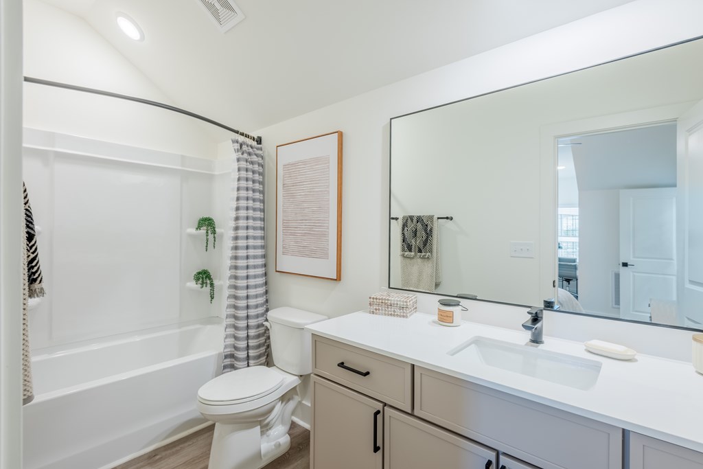 A white bathroom with a toilet, sink, and mirror.