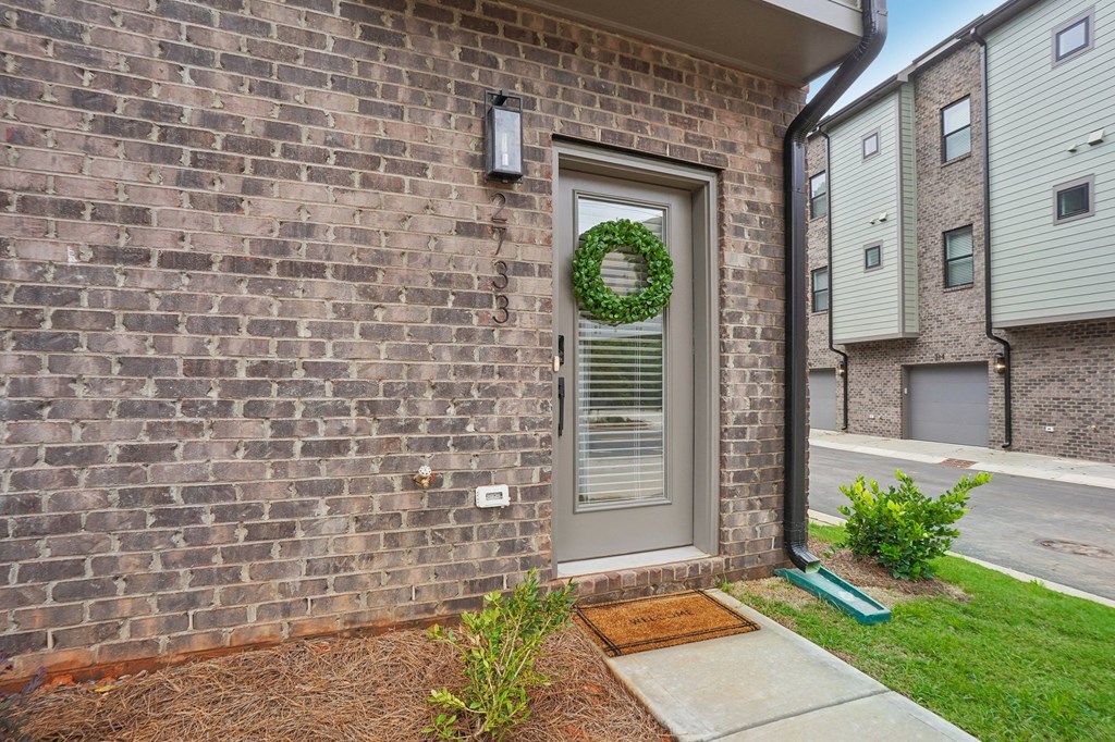 the front door of a brick apartment building with a wreath on the door at The Collection Charlotte in Charlotte, NC, 28205