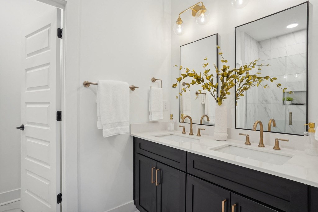 a white bathroom with black cabinets and a sink and a mirror at The Collection Charlotte in Charlotte, NC, 28205