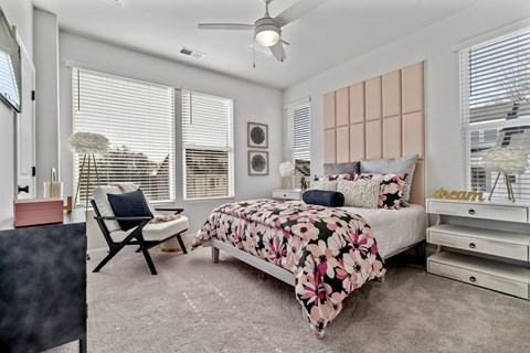 A bedroom with a bed, chair, and a ceiling fan.