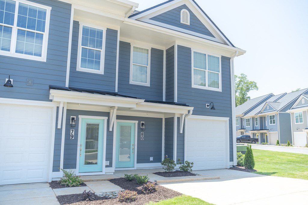 a house with blue siding and white garage doors at Landon Green Artisan Cottages Apartments, Hickory, 28601