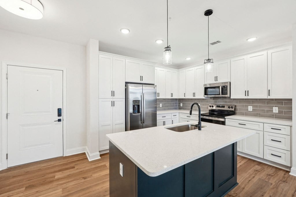 A kitchen with white cabinets and a dark island.
