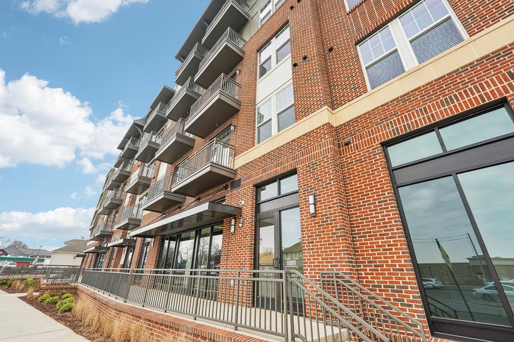A red brick building with a balcony and a glass door.