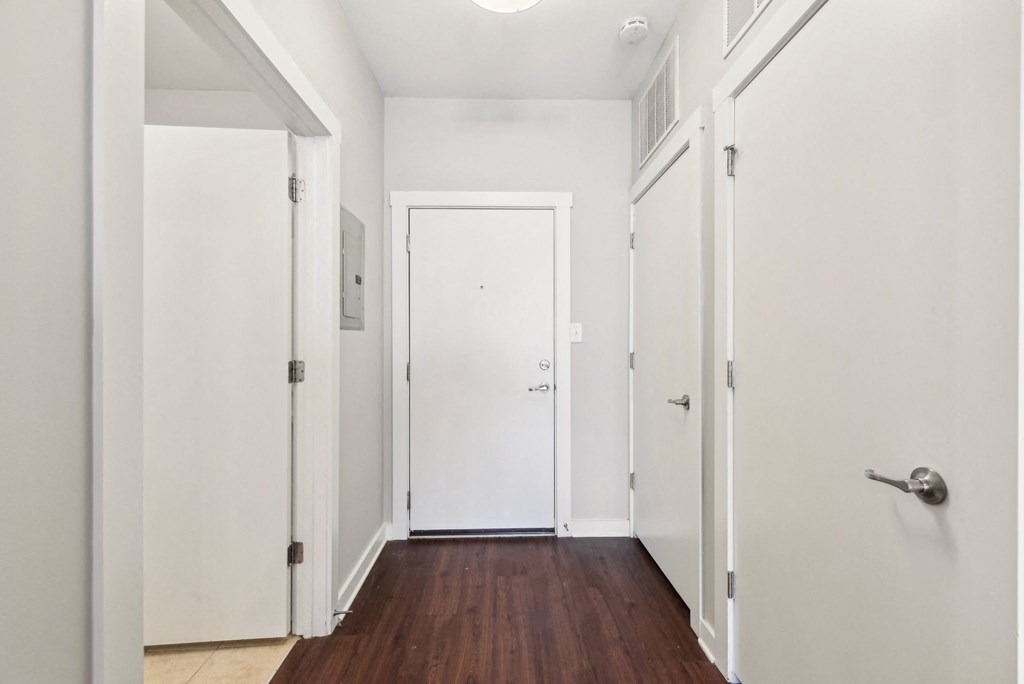 A hallway with white doors and a wooden floor.