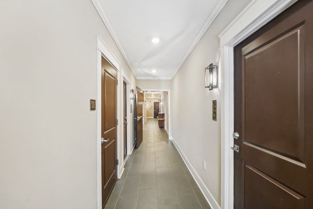 A long hallway with brown doors and white walls.