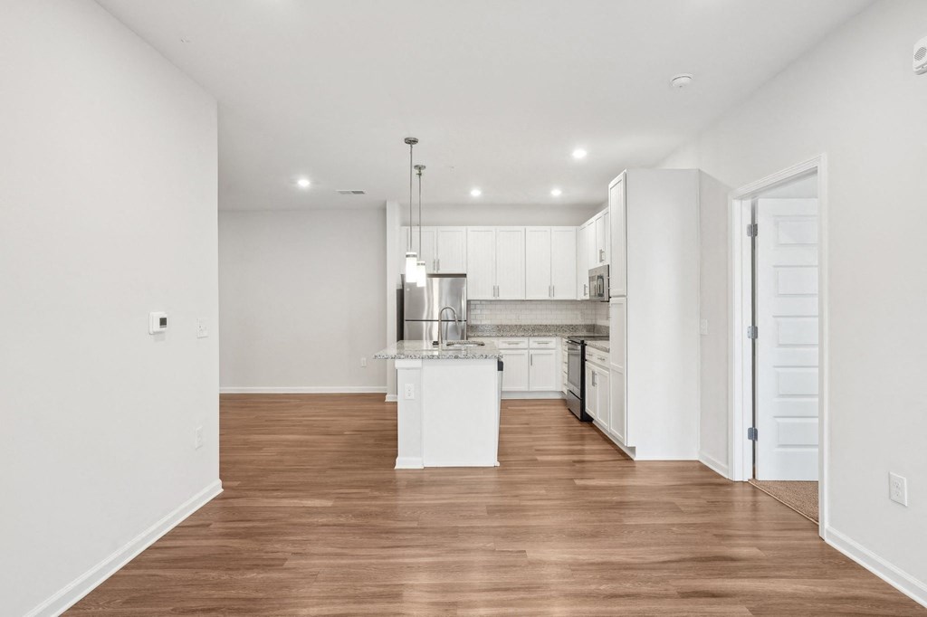 A kitchen with white cabinets and a wooden floor.