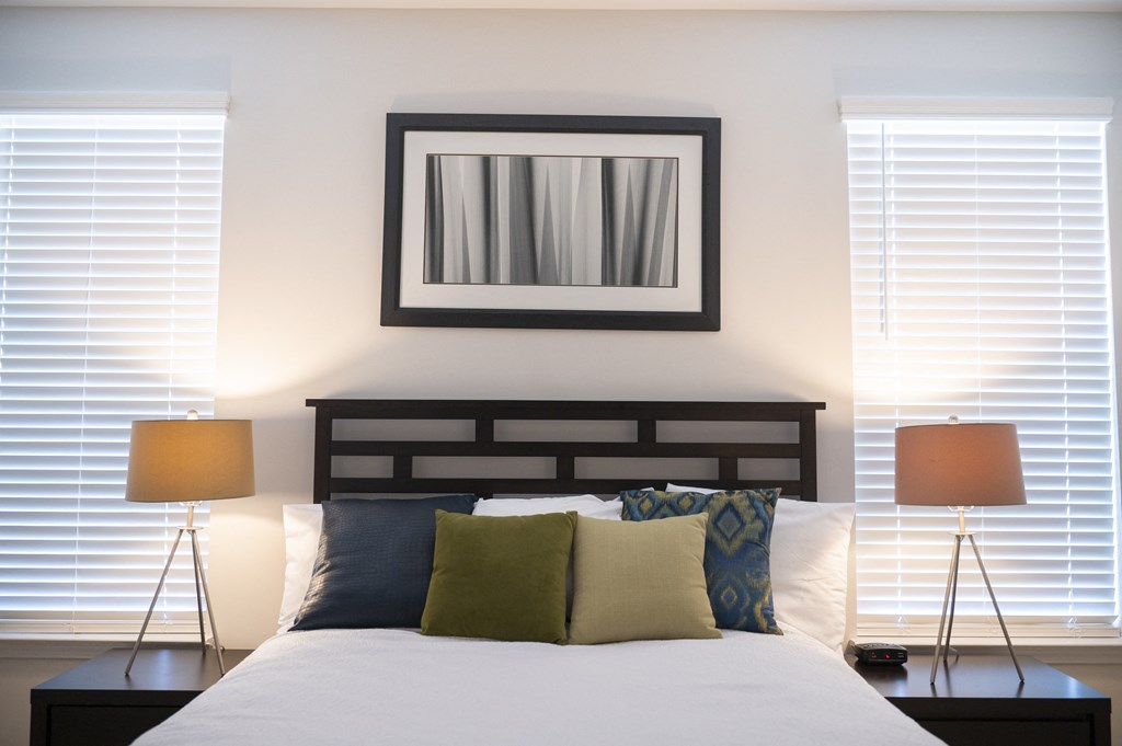 a bedroom with two windows with white blinds and a bed with white pillows and green a bedroom with two windows with white blinds and a bed with white pillows and green at Landon Green Artisan Cottages Apartments, Hickory, NC