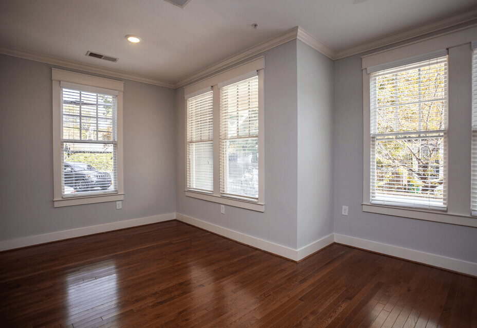 A room with wooden floors and three windows.