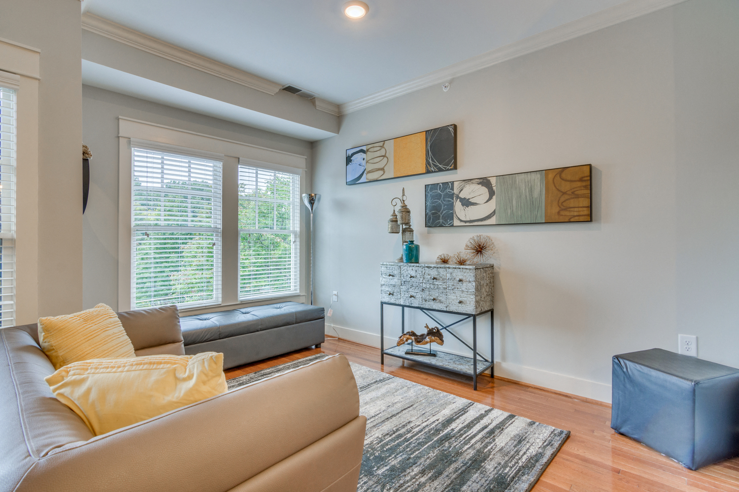 A living room with a grey couch and a yellow pillow.