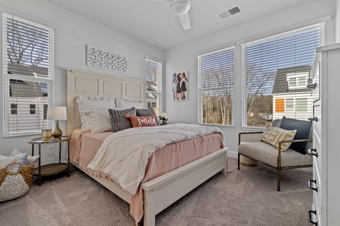 A bedroom with a large bed and a window with blinds.