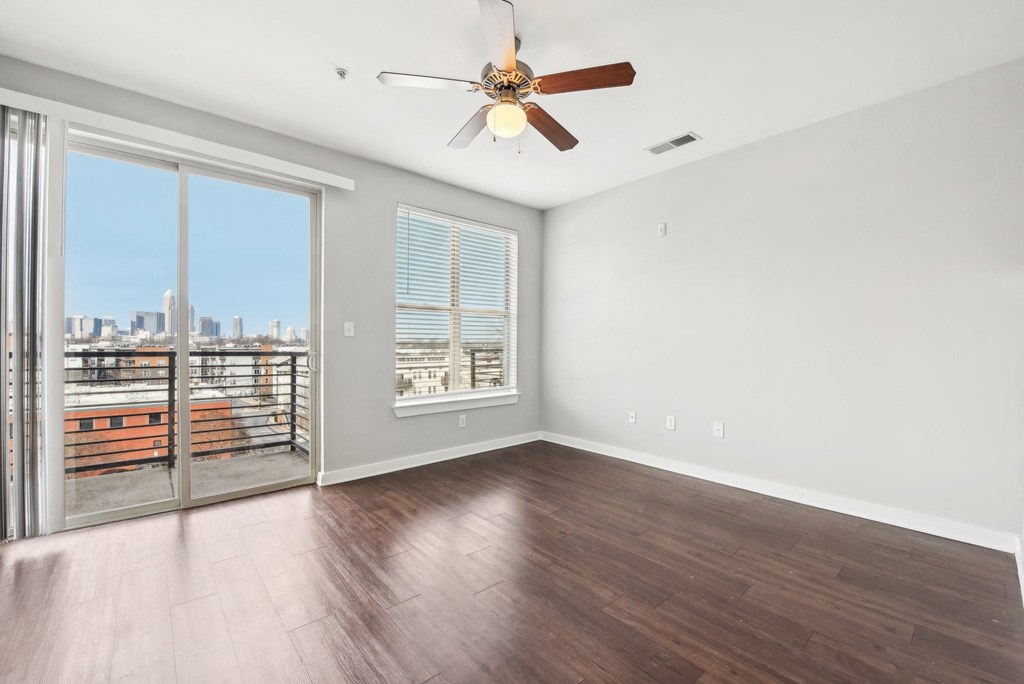 A room with a ceiling fan and sliding glass doors leading to a balcony.
