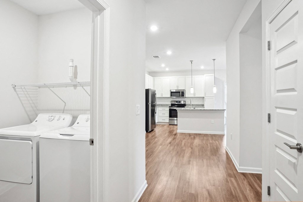 A white kitchen with wood floors and a white fridge.