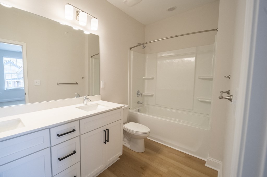 a bathroom with a white sink and toilet next to a white bathtub with a shower curtain at Landon Green Artisan Cottages Apartments, Hickory, 28601