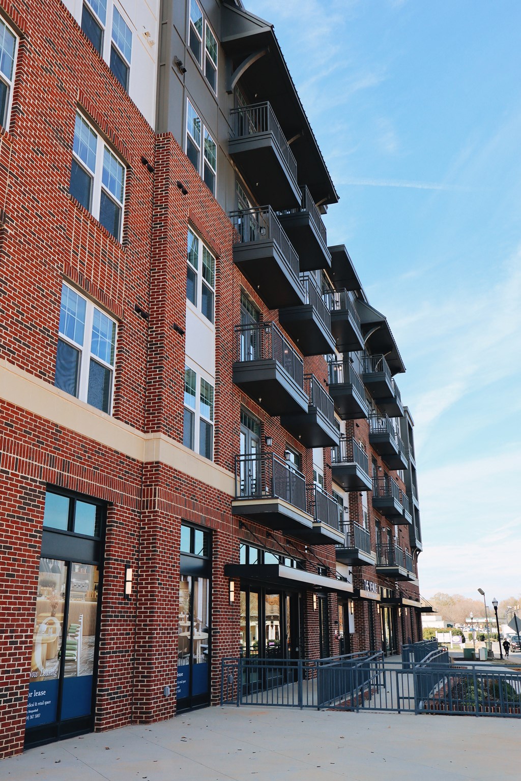 A red brick building with balconies and a black gate in front.