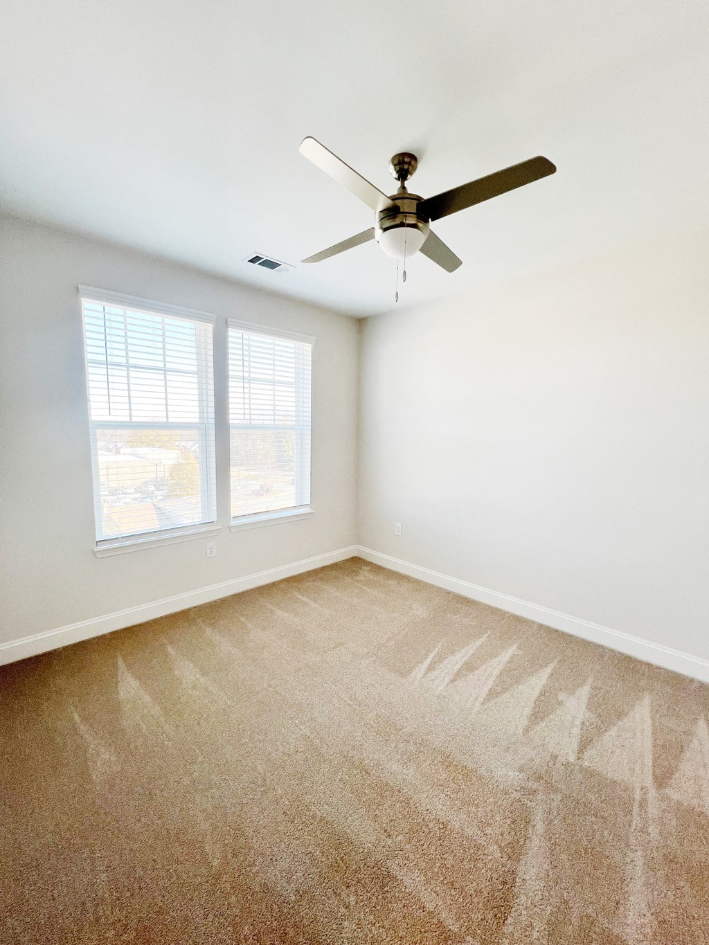 A room with a ceiling fan and carpeted floor.