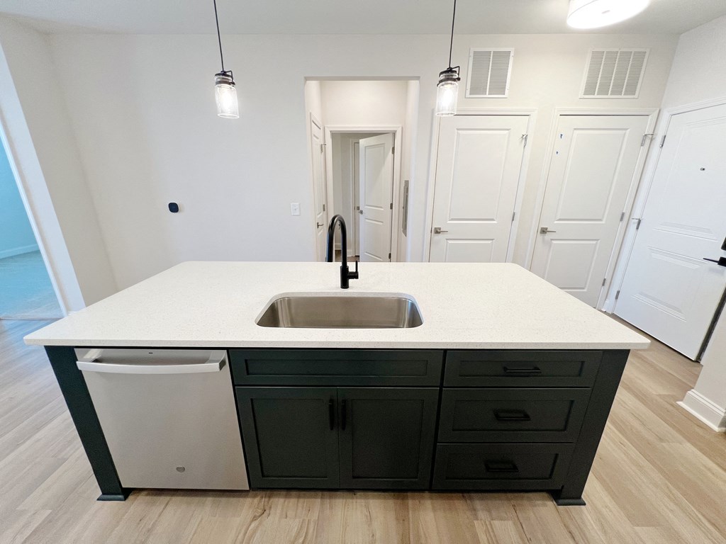 A kitchen with a sink and a trash can.