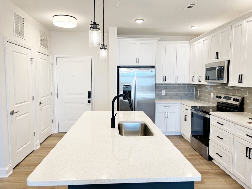 A kitchen with white cabinets and a marble countertop.