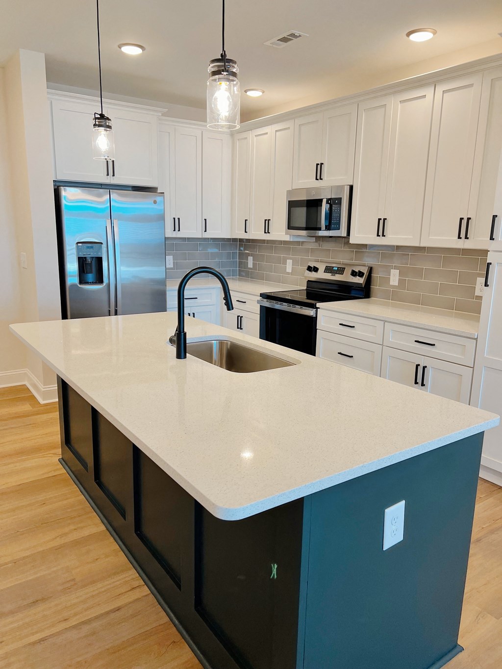 A kitchen with a white counter top and a black drawer.