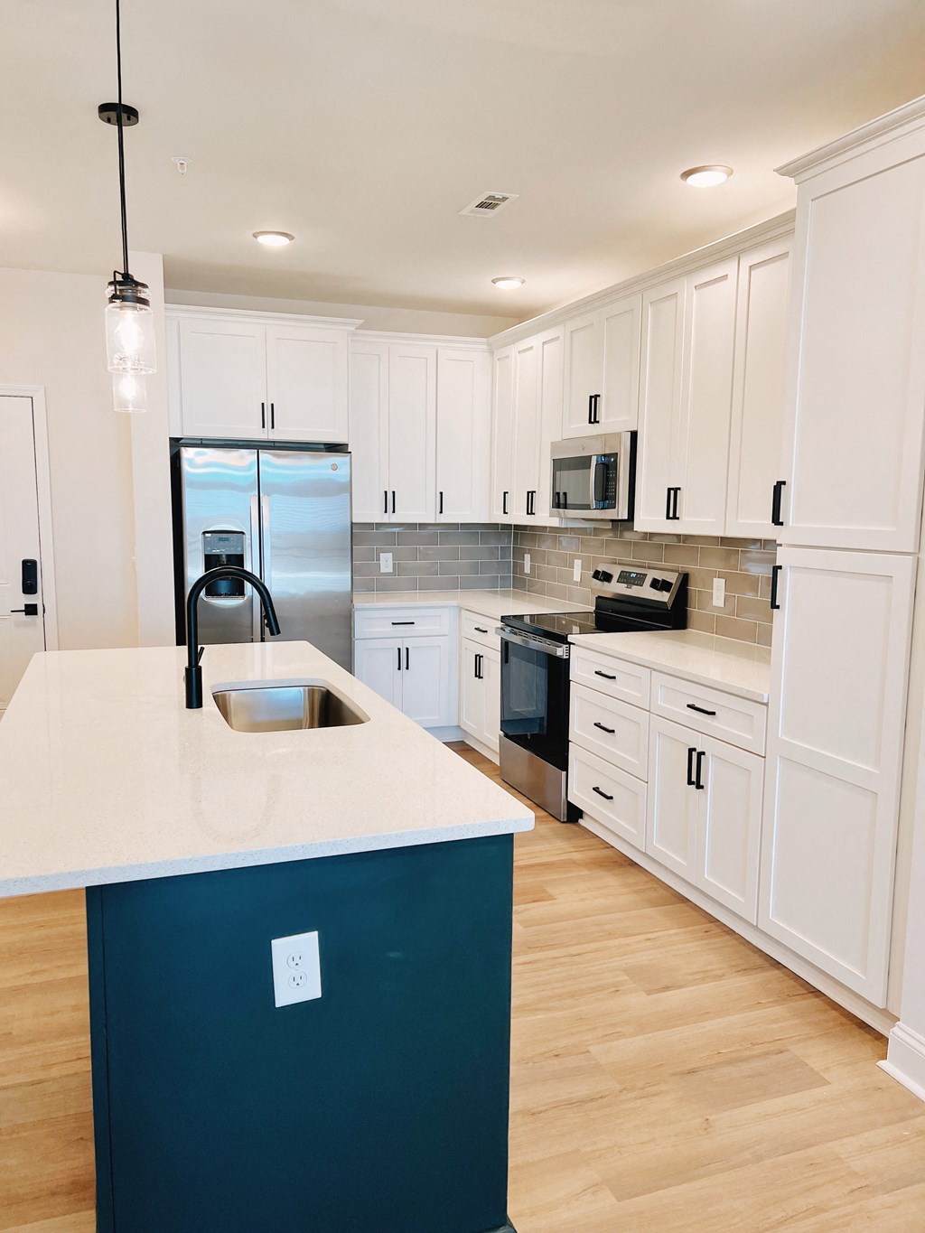 A kitchen with white cabinets and a dark blue island.