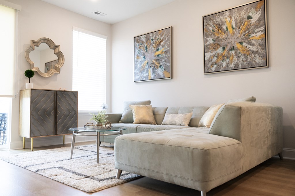 a living room with a beige couch and two paintings on the wall at Landon Green Artisan Cottages Apartments, North Carolina
