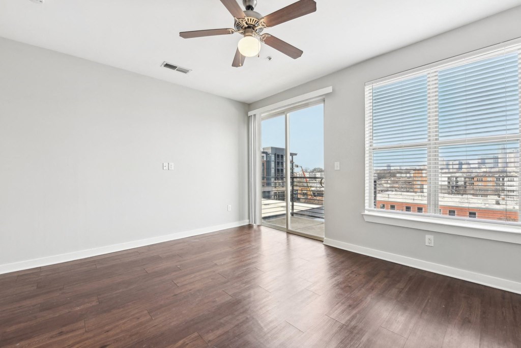 A room with a ceiling fan and sliding glass doors.