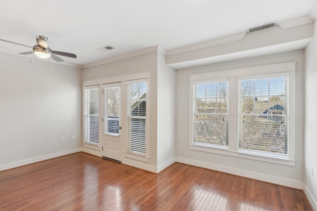 A room with a ceiling fan and sliding glass doors.