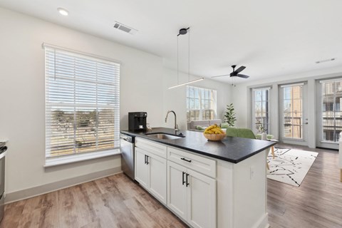 A kitchen with white cabinets and a black countertop.
