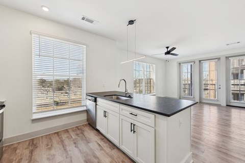 A kitchen with white cabinets and a black countertop.